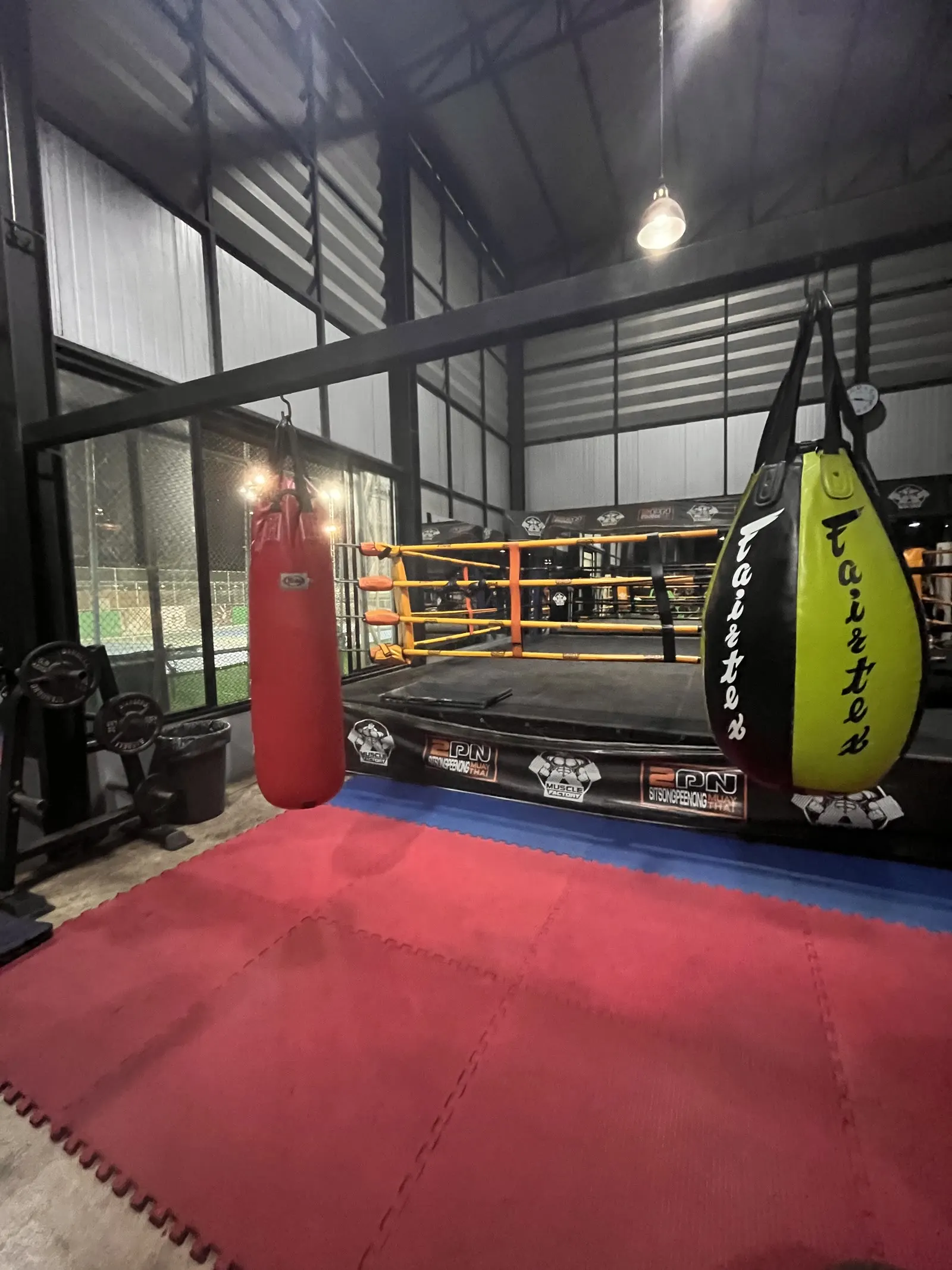 A Muay Thai gym with a boxing ring and heavy bags